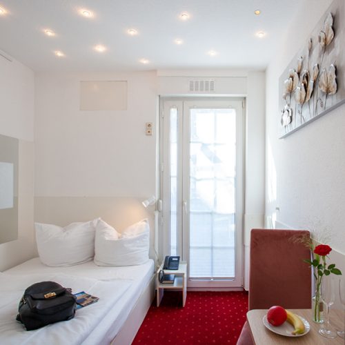 Zimmer mit rotem Teppich und Einzelbett