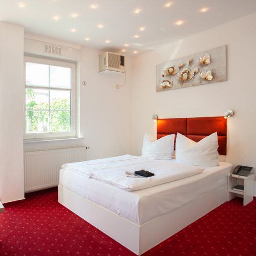 Zimmer mit rotem Teppich und Doppelbett