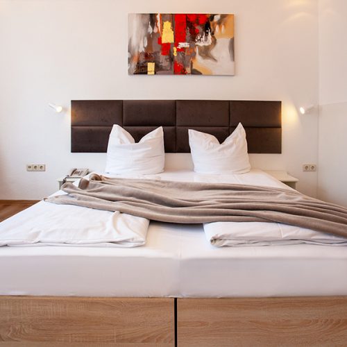 Doppelzimmer mit Bild an der Wand und Fleecedecke auf dem Bett