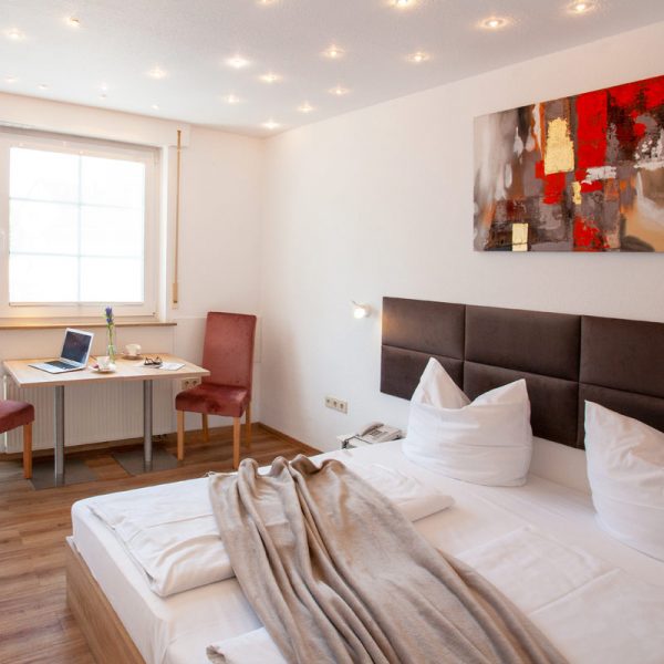 tp-hotelberatung-relax-hotel-standard-doppelzimmer-8 Doppelzimmer mit Bild an der Wand, Fleecedecke auf dem Bett und Sitzecke